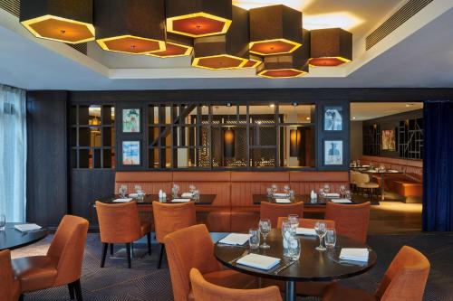 ロンドンにあるダブルツリー バイ ヒルトン ロンドン イーリングのテーブルと椅子、シャンデリアのあるレストラン