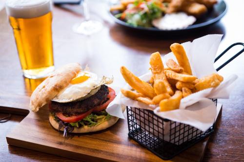 a hamburger and french fries on a table with a glass of beer at The Mulgrave Motel in Mulgrave
