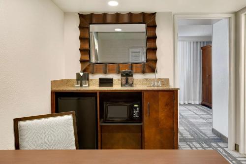 a kitchen with a counter with a microwave and a mirror at Embassy Suites by Hilton Orlando International Drive Convention Center in Orlando