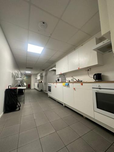 cocina grande con armarios y electrodomésticos blancos en Hostel by Bromma, en Estocolmo