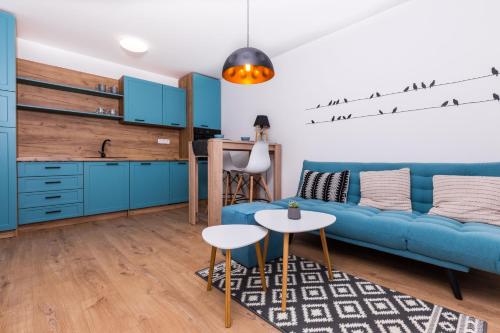 a living room with a blue couch and a kitchen at Netflix & WiFi FREE Dvojizbový byt blízko centra - 24h self check-in in Banská Bystrica