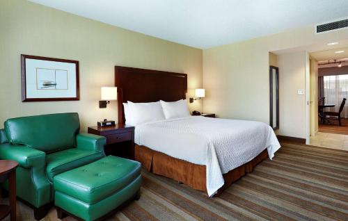 a hotel room with a bed and a green chair at Embassy Suites Parsippany in Parsippany