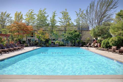a swimming pool at a hotel with chairs and trees at Hilton Seattle Airport & Conference Center in SeaTac