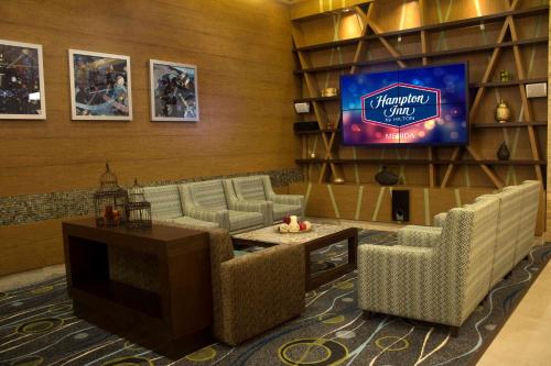 a lobby with couches and a tv in a room at Hampton Inn by Hilton Merida in Mérida