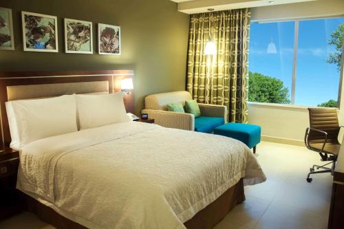 1 dormitorio con 1 cama, 1 silla y 1 ventana en Hampton Inn by Hilton Merida, en Mérida