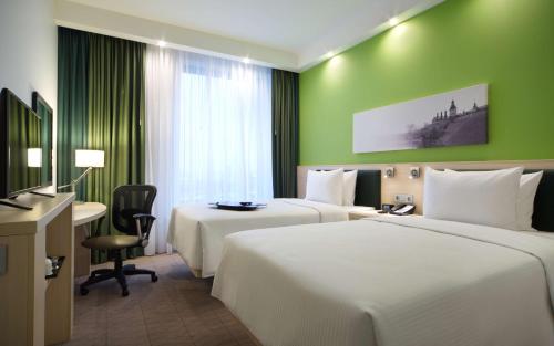 a hotel room with two beds and a desk at Hampton by Hilton Minsk City Centre in Minsk