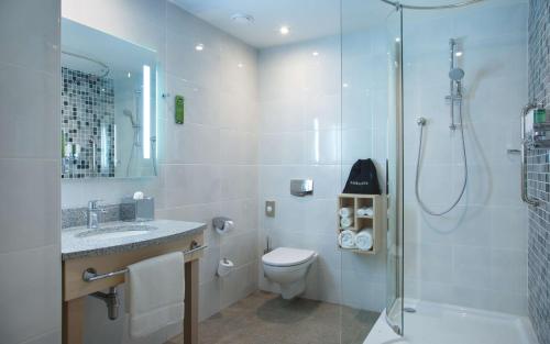 a bathroom with a shower and a toilet and a sink at Hampton by Hilton Minsk City Centre in Minsk