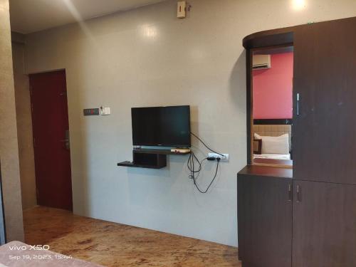 een kamer met een flatscreen-tv aan de muur bij CAUVERY PARADISE in Mayiladuthurai