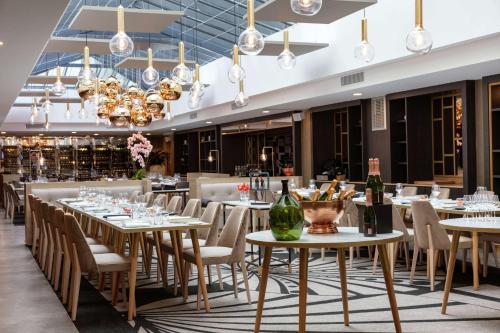 une salle à manger avec des tables, des chaises et des lustres dans l'établissement Niepce Paris, Curio Collection By Hilton, à Paris