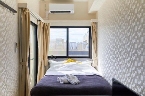 een slaapkamer met een bed en een raam met schoenen erop bij Skytree View Kinshicho - Self Check-In Only in Tokyo