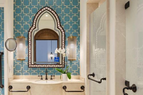 a bathroom with a sink and a mirror at Hilton Salwa Beach Resort and Villas in Abū Samrah