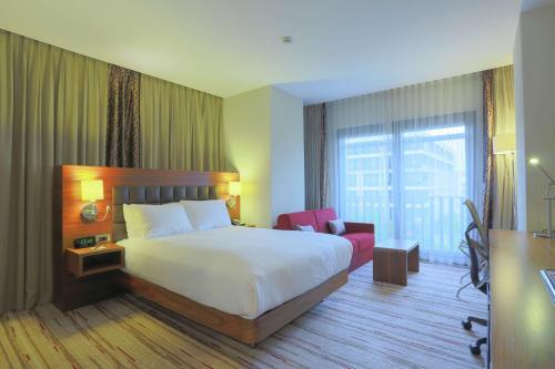 a hotel room with a bed and a red chair at Hilton Garden Inn Eskisehir in Eskisehir