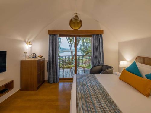 a hotel room with a bed and a balcony at Mercure Goa Devaaya Resort in Old Goa