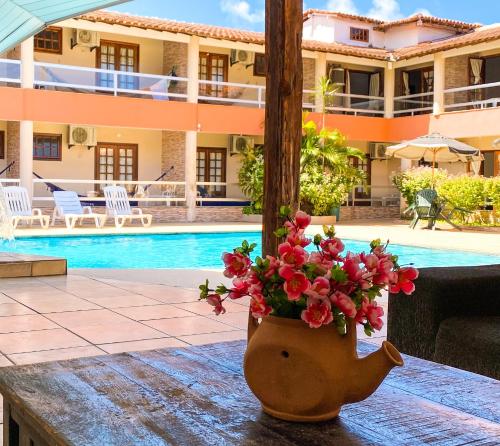 a vase of flowers sitting on a table next to a swimming pool at Hotel Malibu in Porto Seguro