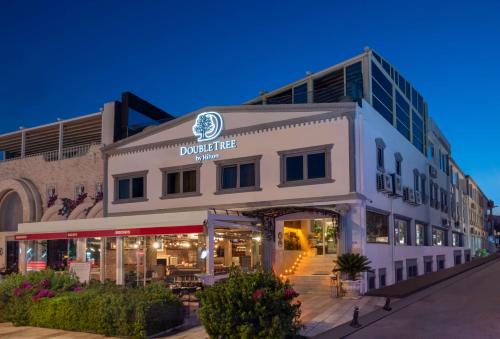 a large white building with a restaurant in front of it at DoubleTree by Hilton Bodrum Marina Vista in Bodrum City