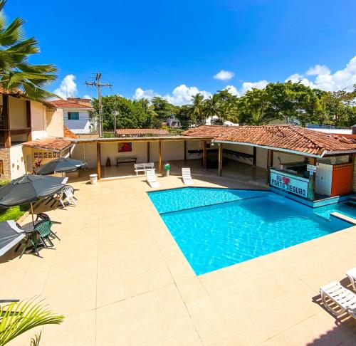 a swimming pool with chairs and umbrellas on a patio at Hotel Malibu in Porto Seguro