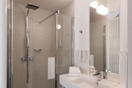 a bathroom with a shower and a sink and a mirror at SOZO Hotel in Nantes