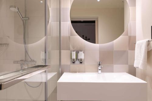a bathroom with a sink and a shower and a mirror at Hampton by Hilton Ashford International in Ashford
