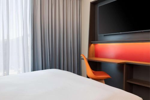 a hotel room with a bed and a flat screen tv at Hampton by Hilton Ashford International in Ashford
