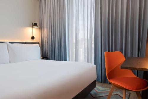 a hotel room with a bed and a chair and a desk at Hampton by Hilton Ashford International in Ashford