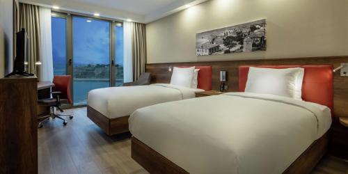 ゲリボルにあるHampton by Hilton Canakkale Geliboluのベッド2台、デスク、テレビが備わるホテルルームです。