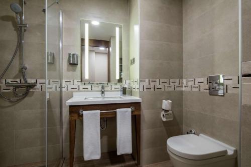 a bathroom with a sink and a toilet and a mirror at Hampton by Hilton Canakkale Gelibolu in Gelibolu
