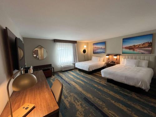een hotelkamer met 2 bedden en een bureau bij La Quinta Inn by Wyndham Columbia NE Fort Jackson in Columbia