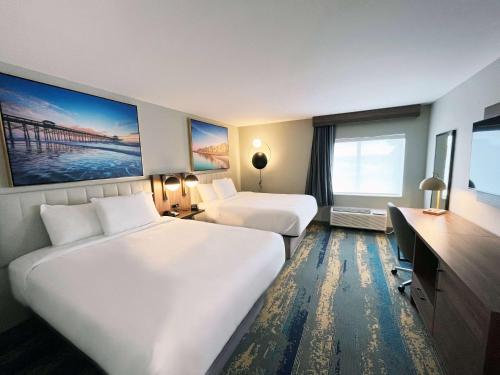 a hotel room with two beds and a television at La Quinta Inn by Wyndham Columbia NE Fort Jackson in Columbia