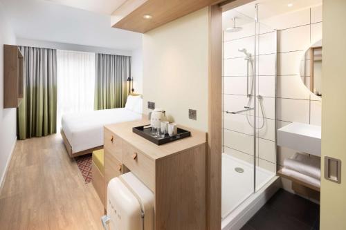 a hotel room with a bathroom with a bed and a shower at Hampton By Hilton Rochdale in Rochdale