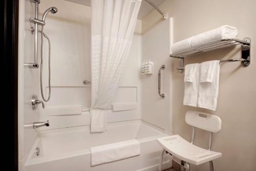 a bathroom with a tub and a shower with towels at Days Inn & Conference Centre by Wyndham Prince Albert in Prince Albert