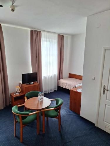 a hotel room with a table and chairs and a bed at Hotel *** NAT Krynica Zdrój in Krynica Zdrój