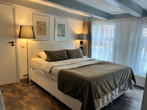 1 dormitorio con cama, lámpara y ventana en Central Guest Rooms, en Ámsterdam