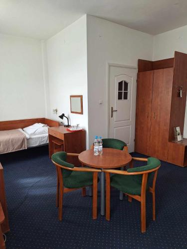 a hotel room with a table and chairs and a bed at Hotel *** NAT Krynica Zdrój in Krynica Zdrój