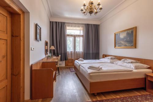 a bedroom with a bed and a desk and a window at Hotel Šipka in Štramberk