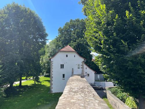 a white building with a stone wall and trees at Dom w murach in Lwówek Śląski