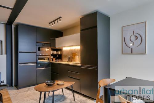 une cuisine avec des armoires noires et une table en bois dans l'établissement 170 - Sublime Flat in Center of Paris, à Paris