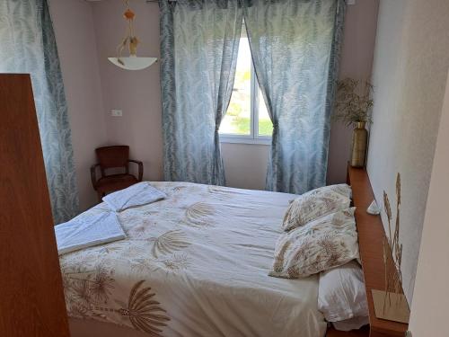 - une chambre avec un lit doté de rideaux bleus et d'une fenêtre dans l'établissement La Mine des 4 pierres, aux Épesses