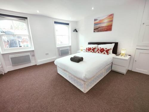 a white bedroom with a large bed and two windows at 3 Bed Flat close to Liverpool st & Brick lane in London