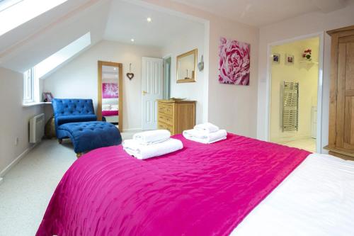 a large bedroom with a large pink bed and a blue chair at Isis Lakes 84 - Tortola Lodge in South Cerney