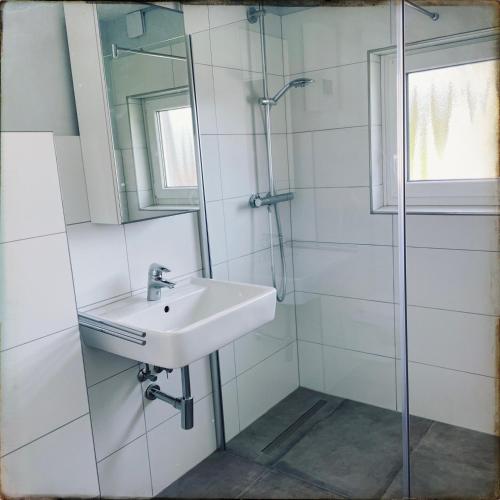 a white bathroom with a sink and a shower at Schöne Penthousewohnung mit Weitblick in Arnsberg