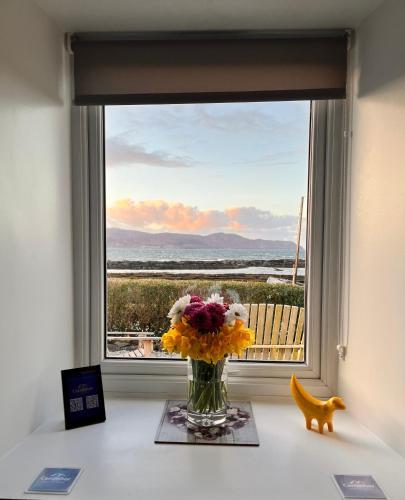 a vase of flowers on a table in front of a window at Carnmhor, Isle of Skye - Stunning 242 year old cottage on its own sea shore! in Breakish