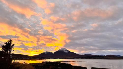 a mountain in the middle of a lake at sunset at Carnmhor, Isle of Skye - Stunning 242 year old cottage on its own sea shore! in Breakish