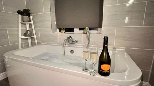a bottle of champagne and two glasses in a bath tub at Carnmhor, Isle of Skye - Stunning 242 year old cottage on its own sea shore! in Breakish