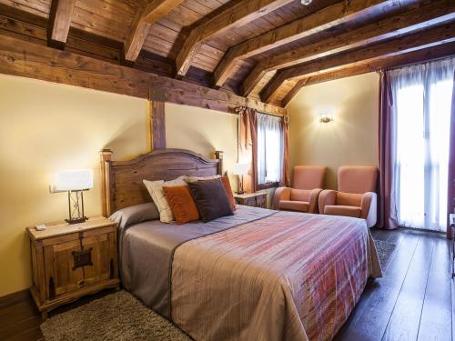 a bedroom with a large bed and a chair at Hotel Rural Irati in Jaurrieta