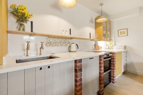 a kitchen with white cabinets and a sink at Horseshoe Cottage Farm with Hot Tub in Leicester