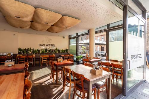 a restaurant with wooden tables and chairs and windows at DAS WESEL - DEIN HOTEL AM RHEIN in Oberwesel