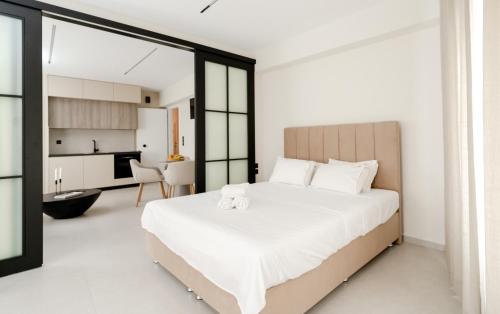 a bedroom with a large white bed and a kitchen at KHouses A2 in Arta