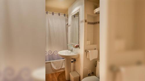 W łazience znajduje się umywalka, toaleta i lustro. w obiekcie Hotel A Nieu w mieście Jaca