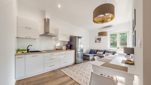 a kitchen with white cabinets and a living room at Dwie Sosny z sauną, Sun & Snow in Ustronie Morskie