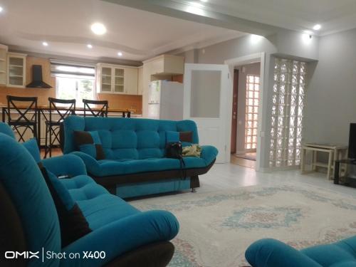 a living room with a blue couch and a kitchen at ferah havaalanı 10 sahile 1 km yeşillikler içinde in Altınkum